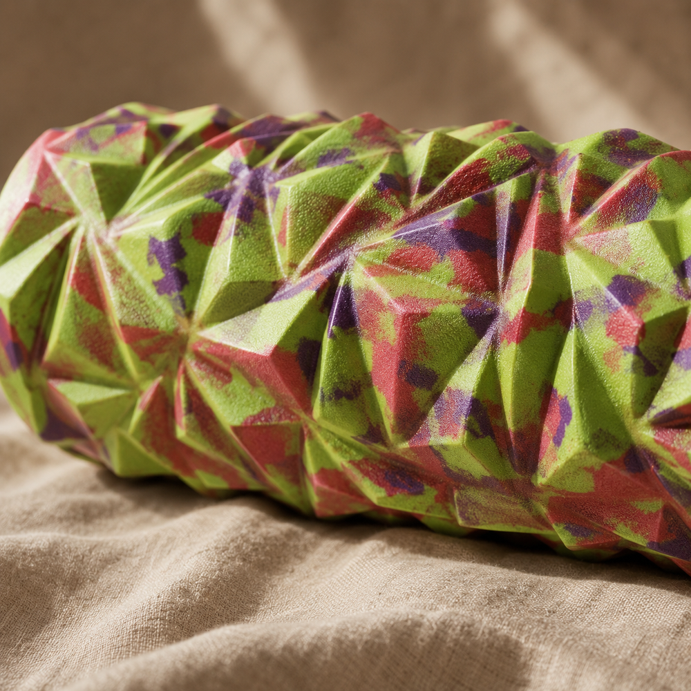 Textured close-up of the Peak Deep Tissue Trigger-Point Foam Roller in camo green, red and purple, resting on natural linen in warm evening light
